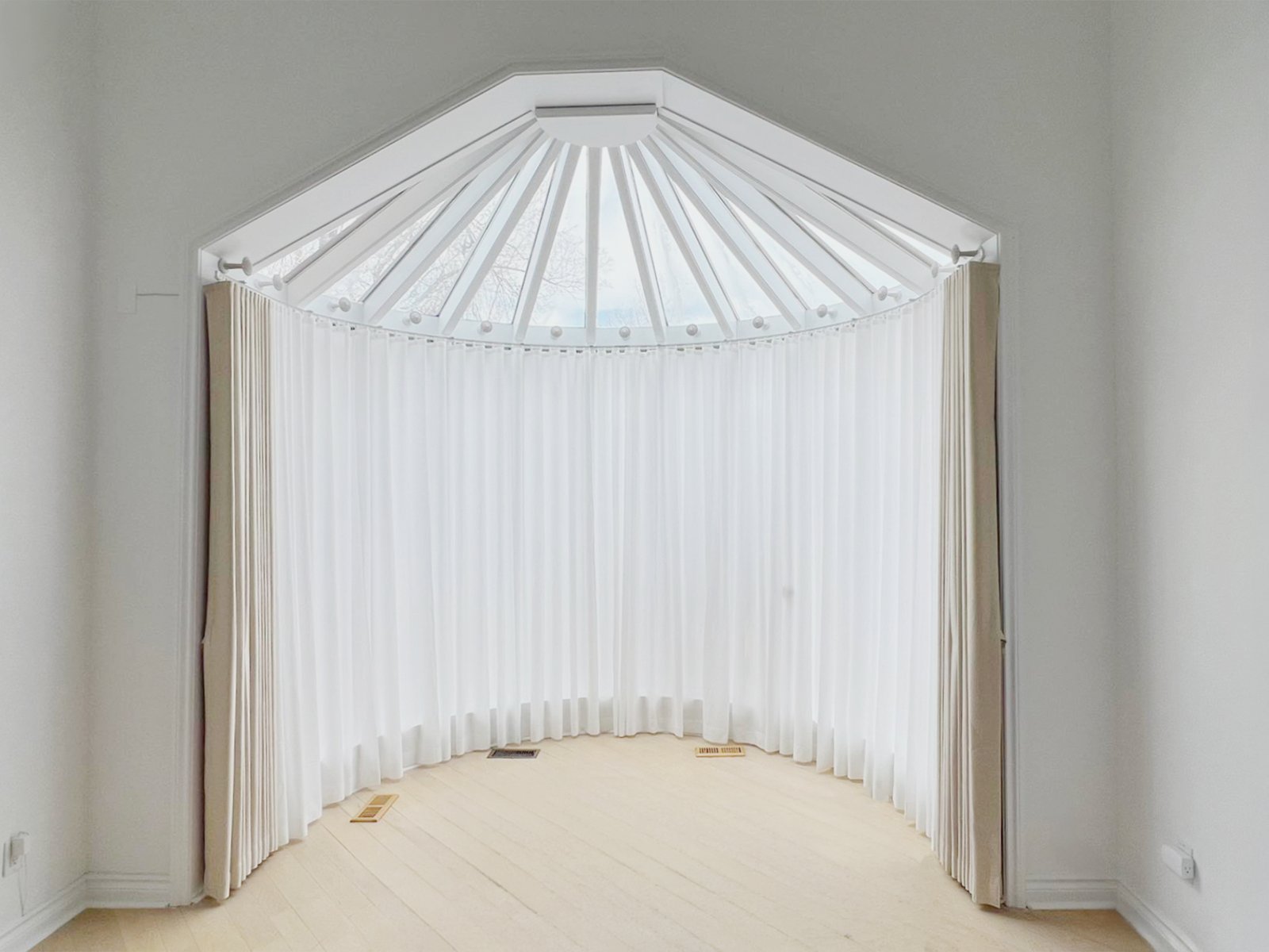 Bay window layered curtain and sheer treatment on a custom curved track — Starlight Shutter Toronto