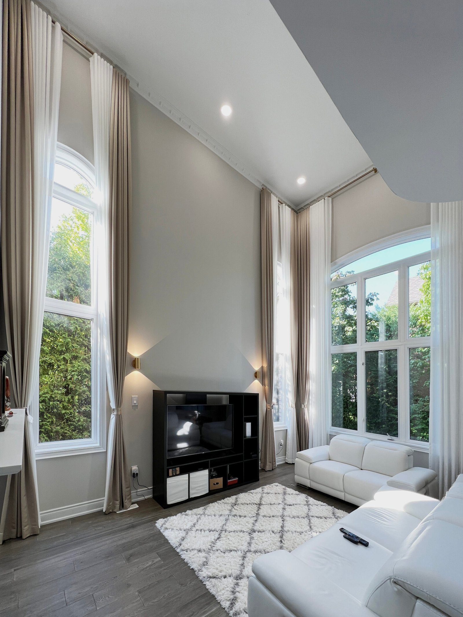 Ivory pinch-pleat blackout drapery tied back beside a window with a light-filtering shade