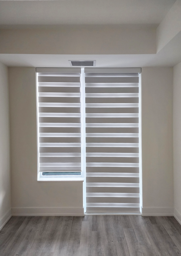 Light-filtering zebra blinds with alternating sheer and solid grey horizontal fabric bands installed on two adjacent windows.