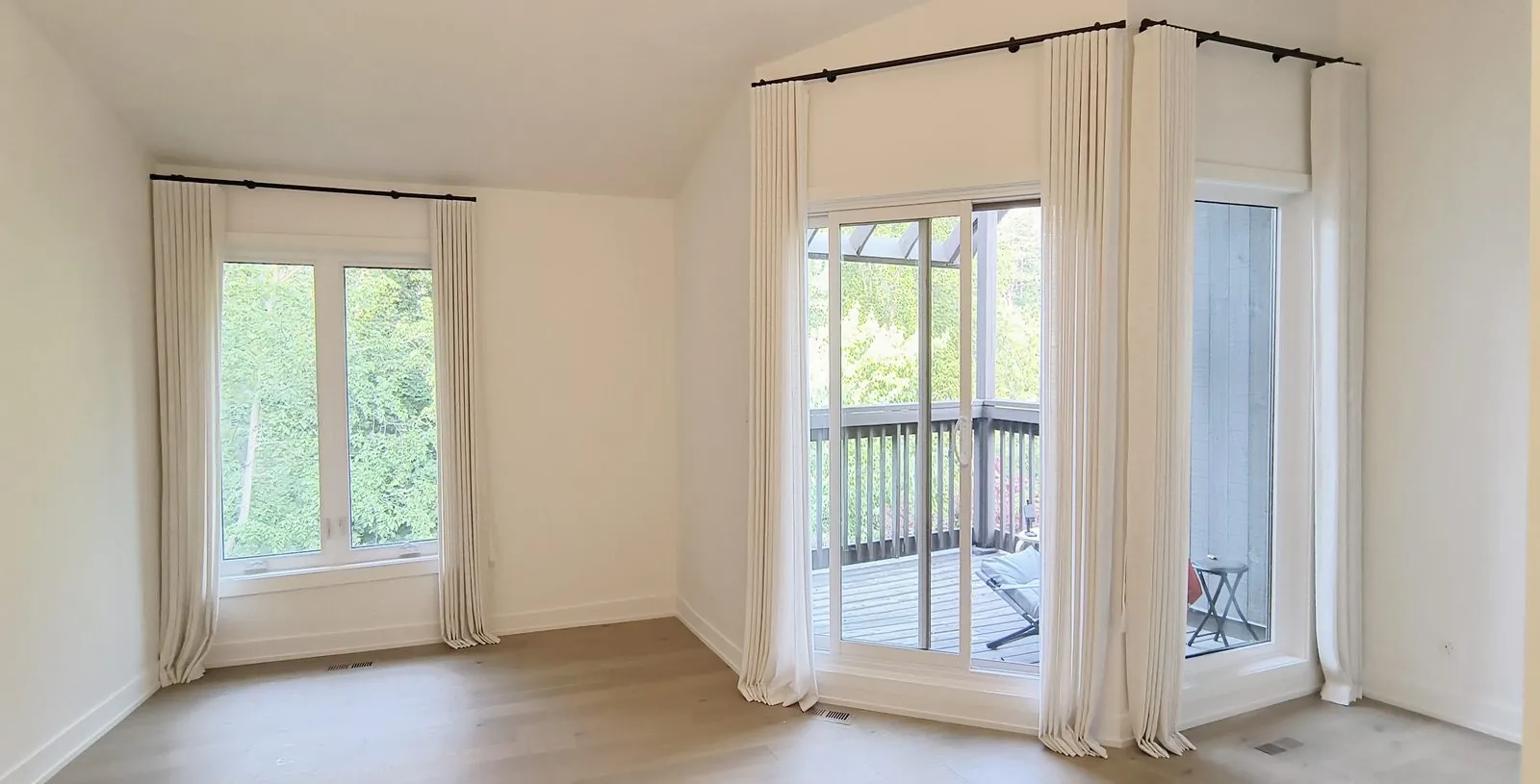 Full-height linen drapery on tall corner windows and a patio door in a vaulted Toronto room