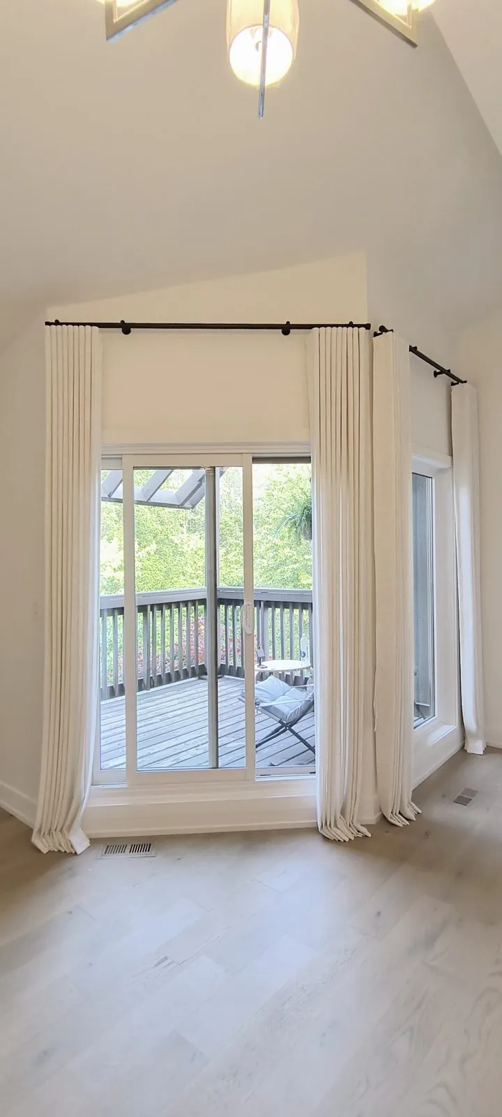 Tailored linen pinch-pleat drapery on corner sliding doors in a Toronto home