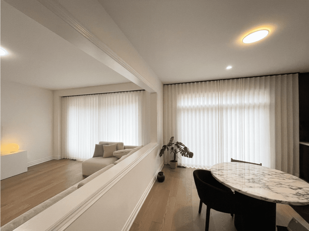 Elegant floor-to-ceiling white sheer curtains providing privacy and soft light filtering across a modern living room and dining room in Toronto.