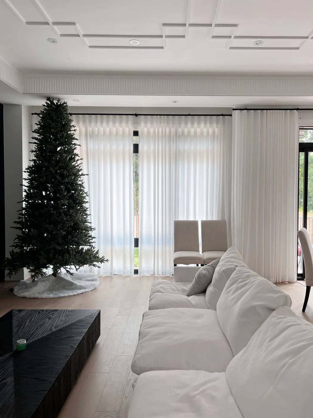 White ripplefold sheer drapery framing floor-to-ceiling windows in a modern Toronto living room