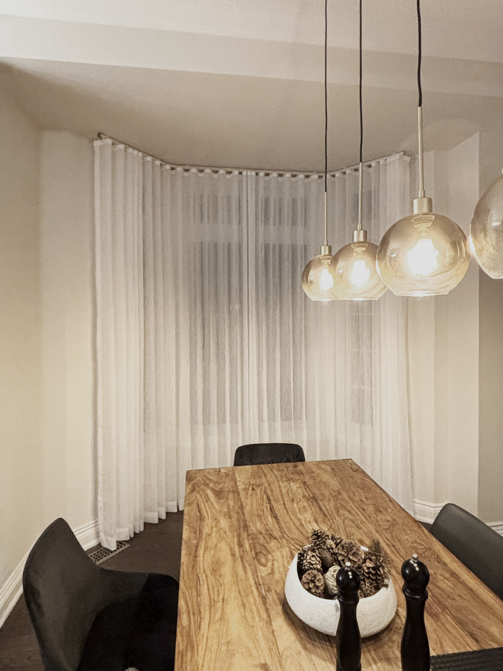 Sheer curtains wrapping a bay window in a Toronto dining room
