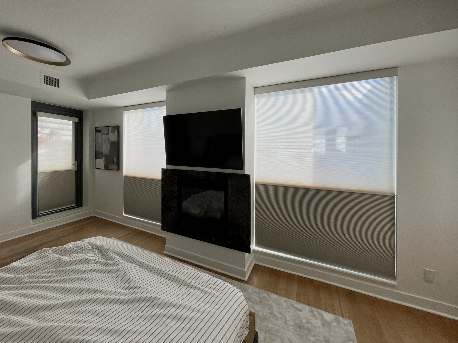 Cellular honeycomb shades with a top-down view on large windows in a bright Toronto bedroom