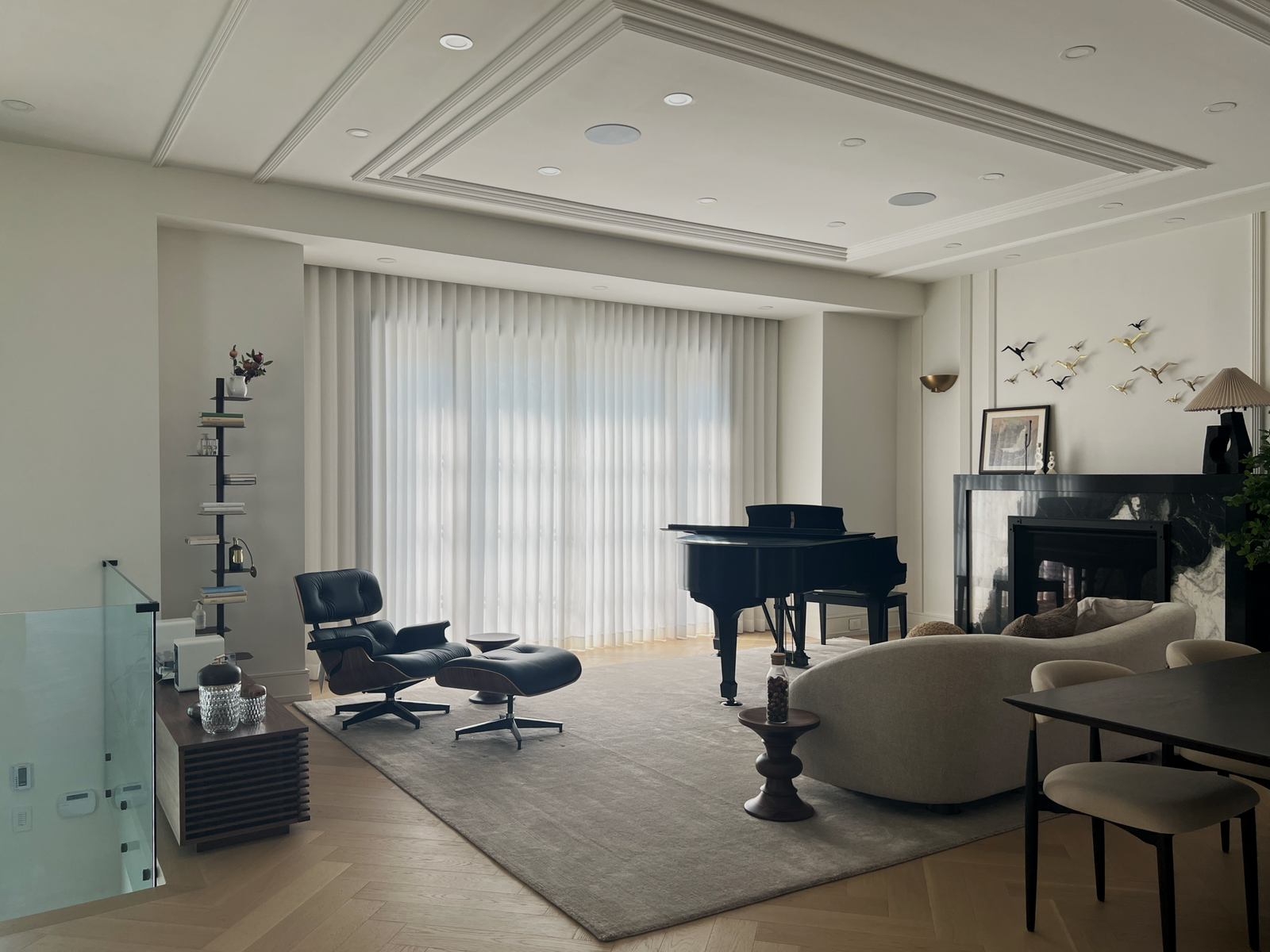 A spacious living room featuring a grand piano set in front of a wide wall of floor-to-ceiling floor-length white sheer curtains. The uniform ripplefold drapery diffuses sunlight across the entire room and light wood herringbone floors.