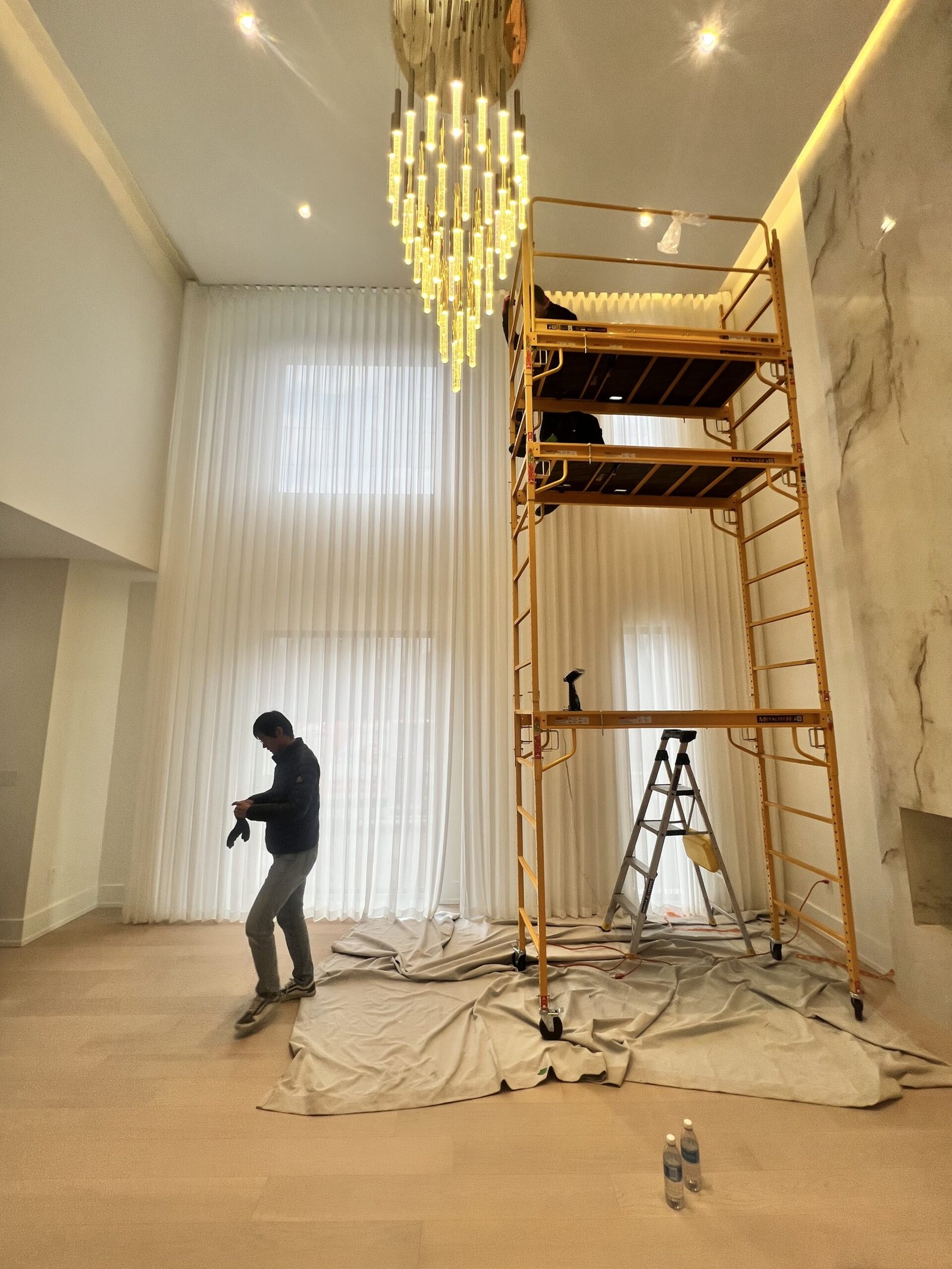 Starlight Shutter installer fitting custom curtains on a high-ceiling window in a Toronto home