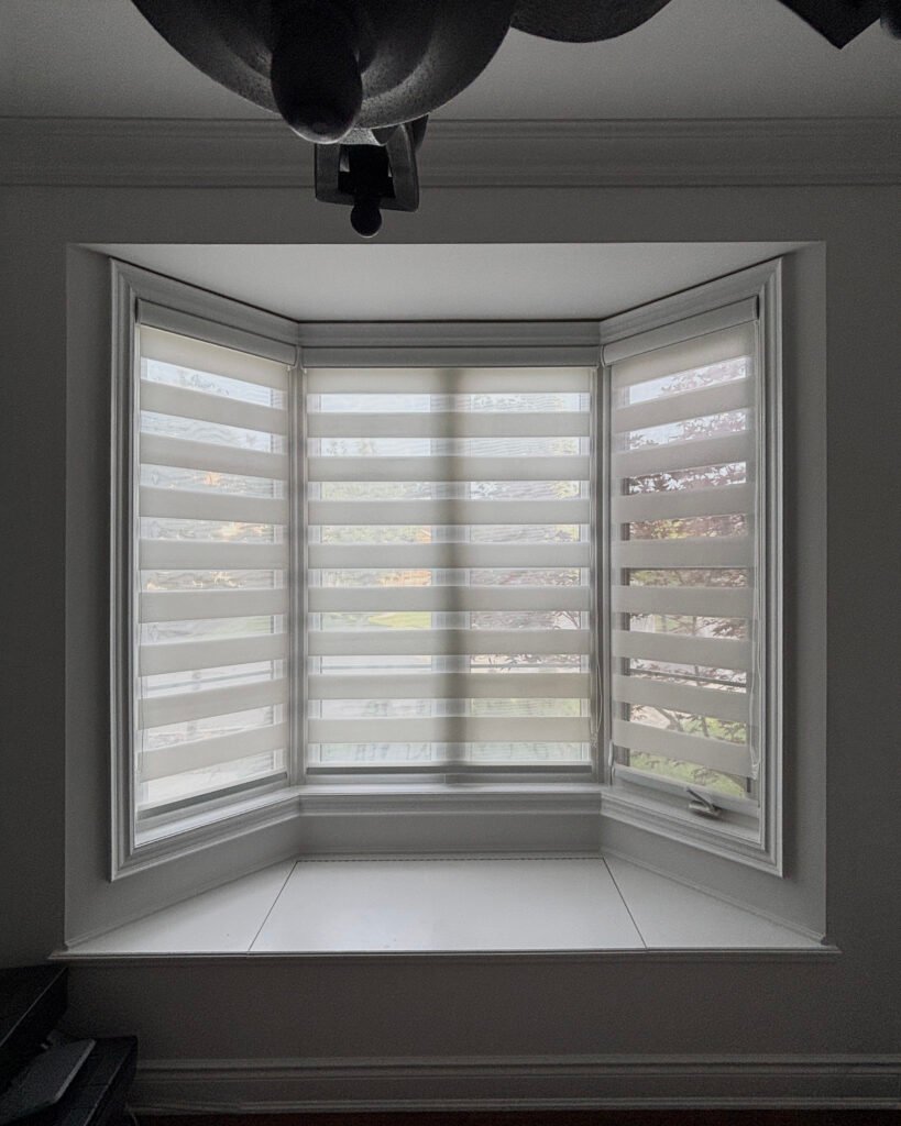 Three light filtering zebra blinds fitted to a bay window in a home office