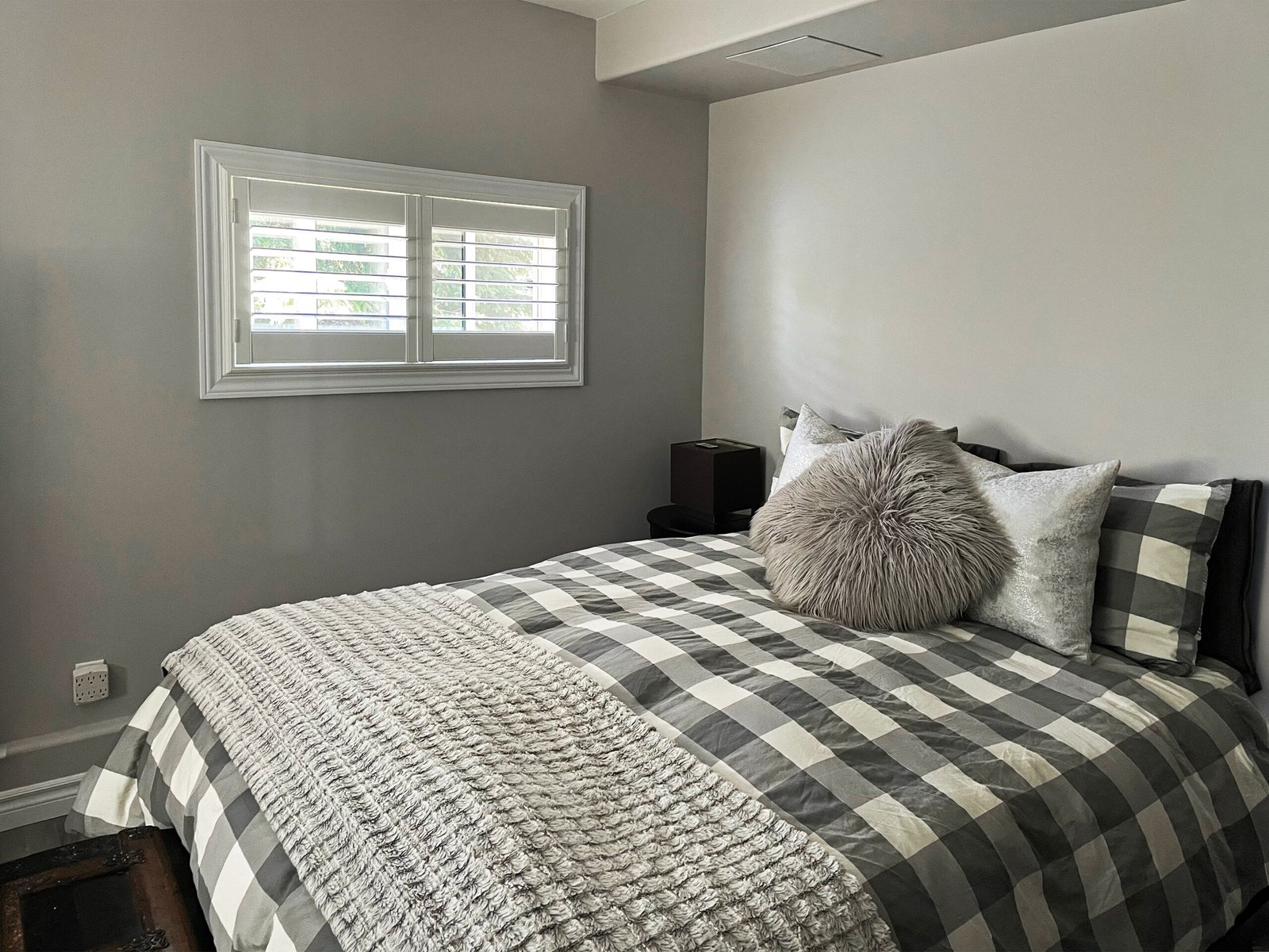 Custom wood shutters in a Toronto bedroom, louvers tilted for morning light