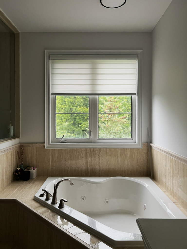 Light filtering zebra blind above a corner tub in a Milton ensuite bathroom