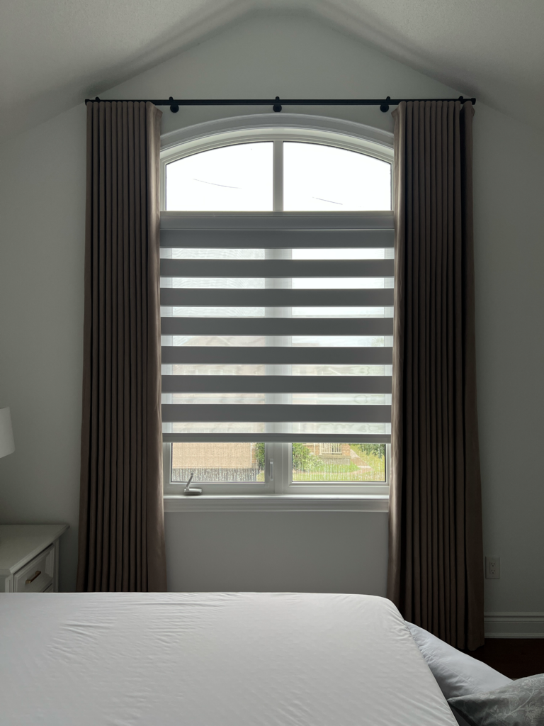 Blackout zebra blind and blackout curtains on an arched window in a Milton children's bedroom.